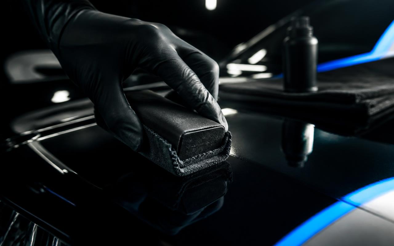 Gloved hand applying liquid ceramic coating with a suede applicator to glossy black paint in Lewisville, NC