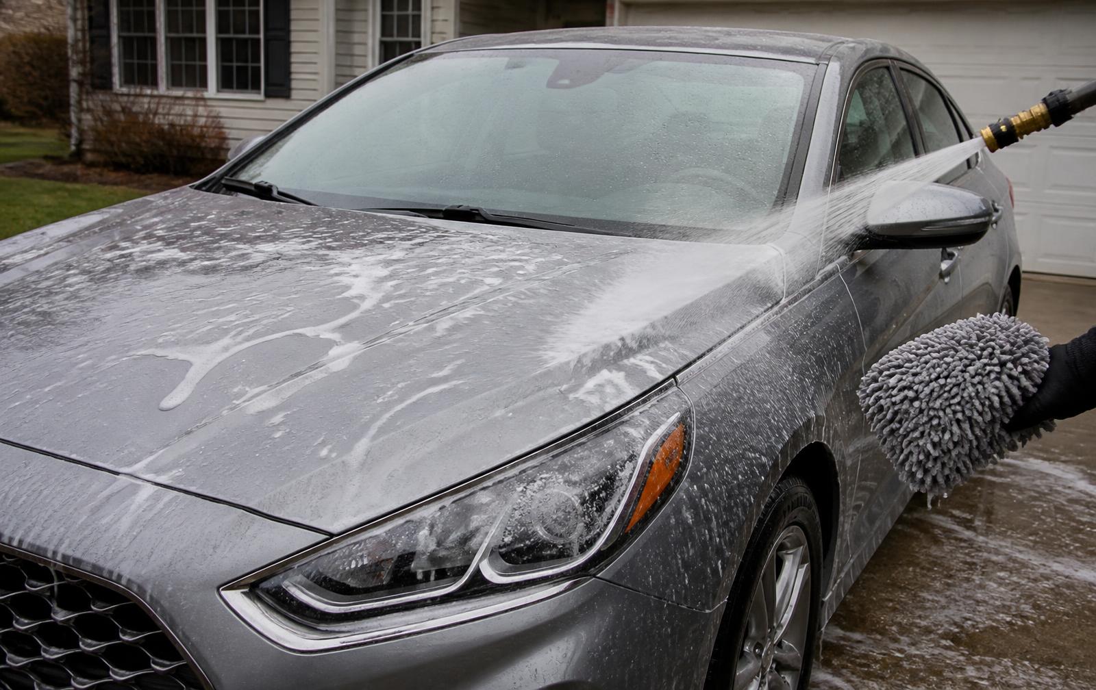 Pressure washer rinsing suds off a glossy black sedan during a professional exterior wash in Lewisville, NC