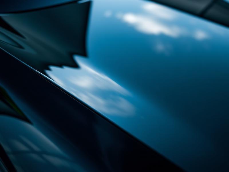 Mirror-finish reflection on a freshly polished glossy black car panel